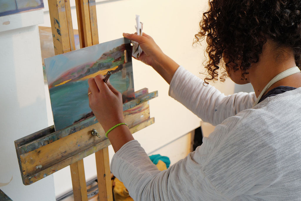 Student painting with oil paints on an easel