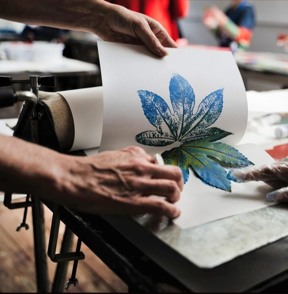 student using press in a print room to create relief print from a leaf copyright Annabel Wilkes